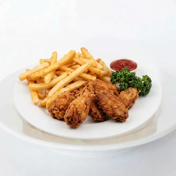Crispy fried chicken wings and golden french fries with ketchup and broccoli on a white plate.
